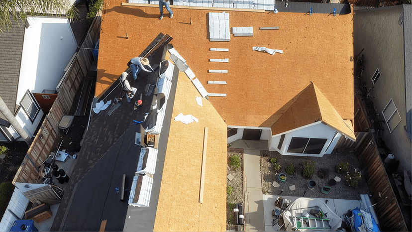 Aerial view of a roof mid-replacement with the old shingles removed down to the decking and new underlayment going on
