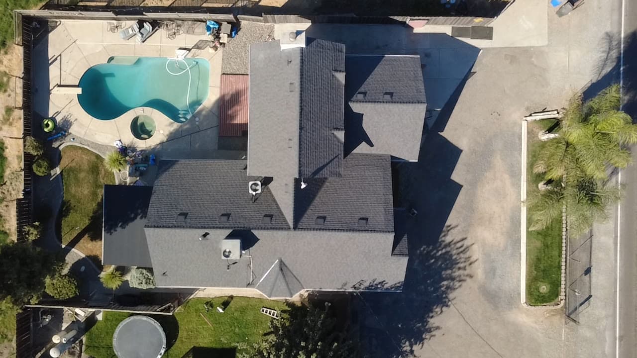 Finished shingle roof seen straight down, pool beside the house