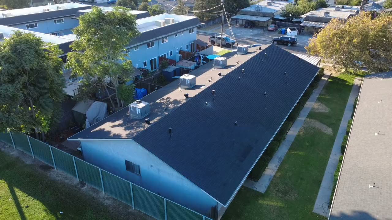 Drone over a low-slope dark roof on an apartment building